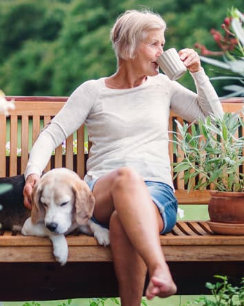 Older woman sits on bench drinking coffee